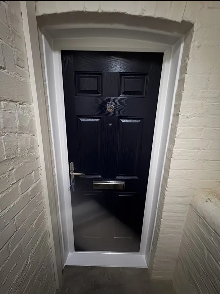Dark panelled residential entrance door within a white painted frame