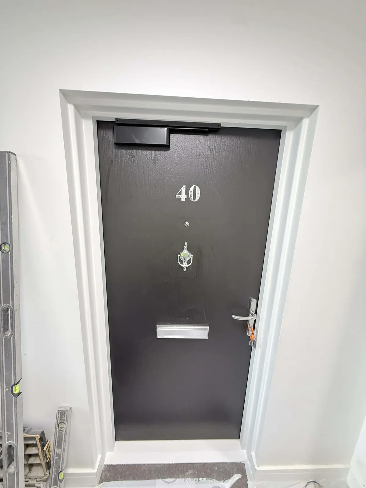 Dark residential entrance door with overhead closer and coordinated ironmongery