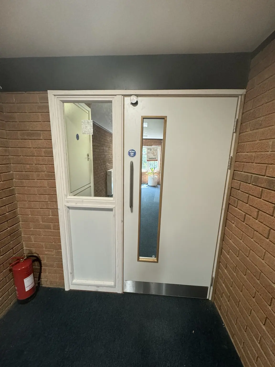 White glazed communal door with adjacent glazed sidelight and metal threshold