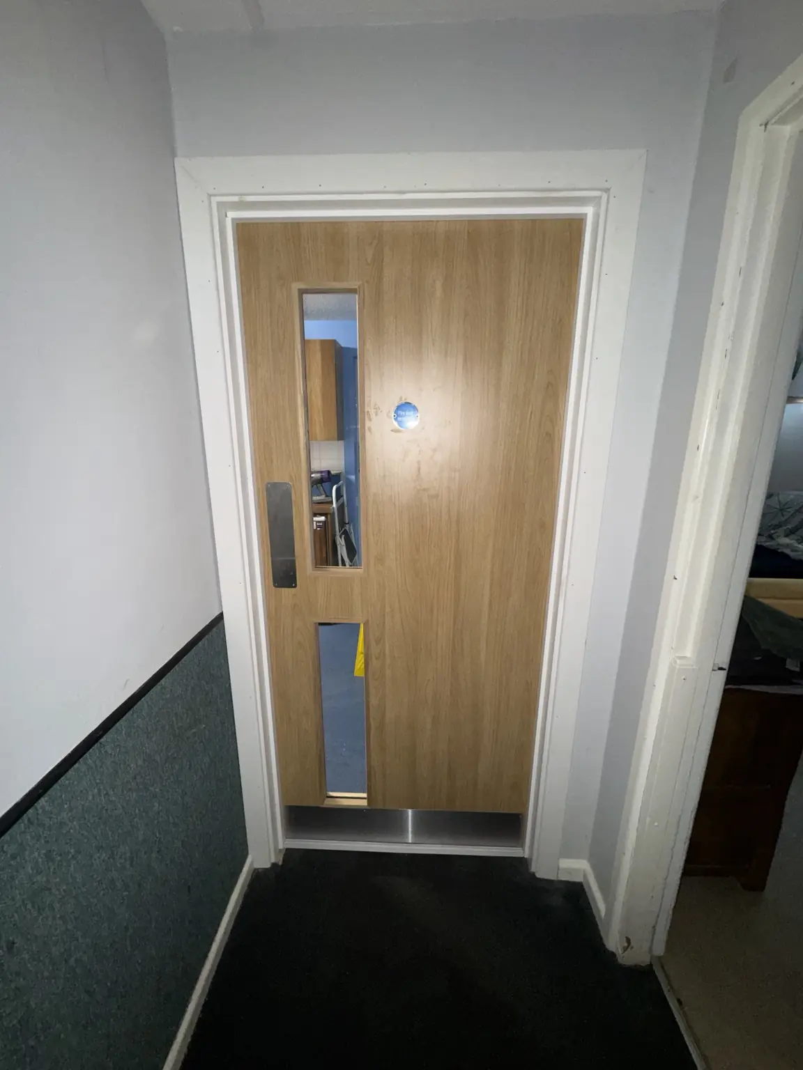 Oak-effect communal door with narrow glazing and coordinated ironmongery